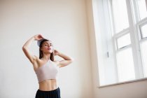 Jeune jolie femme en casquette debout dans un studio de danse hip hop — Photo de stock