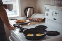 Fried eggs in a frying pan at kitchen at home — Stock Photo