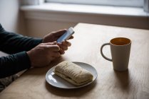Man sitting at table and using mobile phone at home — Stock Photo