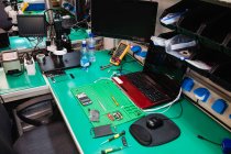 Bureau avec divers équipements dans un centre de réparation électronique — Photo de stock