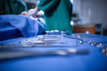 Chirurgische Werkzeuge auf Chirurgentablett mit Chirurg im Hintergrund im Operationssaal des Krankenhauses — Stockfoto