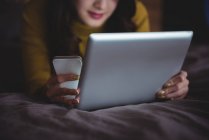 Frau liegt mit digitalem Tablet und Handy im heimischen Schlafzimmer — Stockfoto
