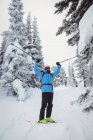 Лыжник, стоящий с лыжами на заснеженном пейзаже — стоковое фото