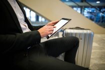 Sección media del hombre de negocios utilizando tableta digital en el aeropuerto - foto de stock