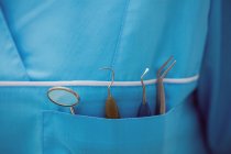 Seção média do dentista carregando ferramentas odontológicas no bolso na clínica odontológica — Fotografia de Stock