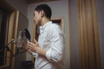 Uomo che canta al microfono in studio di registrazione — Foto stock