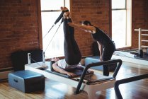 Treinador assistindo mulher enquanto pratica pilates no estúdio de fitness — Fotografia de Stock