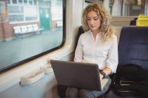 Mulher de negócios cuidadosa usando laptop enquanto viaja — Fotografia de Stock