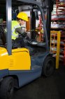 Confident female worker driving forklift in factory — Stock Photo