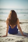 Вид ззаду жінки, що розслабляється на пляжі в сонячний день — стокове фото