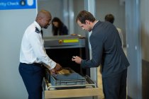 Сотрудник службы безопасности аэропорта проверяет аксессуары пассажиров в аэропорту — стоковое фото