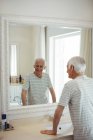 Senior blickt im Badezimmer auf Spiegel — Stockfoto