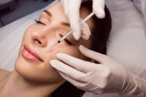Jeune patiente recevant une injection cosmétique sur le visage dans une clinique esthétique — Photo de stock