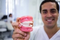 Main du dentiste tenant un ensemble de prothèses dentaires dans une clinique dentaire — Photo de stock