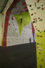 Homme pratiquant l'escalade sur mur d'escalade artificiel dans la salle de gym — Photo de stock