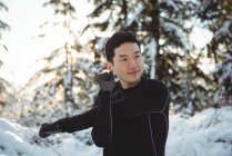 Smiling man stretching arms in forest during winter — Stock Photo