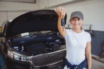 Портрет механіка жінки в гаражі, що тримає ключ автомобіля — стокове фото