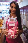Female shopkeeper holding jar of turkish sweets at counter in shop — Stock Photo