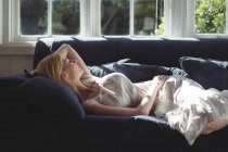 Bella donna che si rilassa sul divano in soggiorno a casa — Foto stock