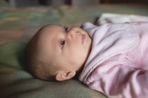 Close-up of cute baby lying on bed in bedroom at home — Stock Photo