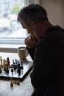 Homme attentif jouant aux échecs à la maison — Photo de stock