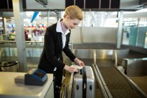 Airline check-in attendant sticking tag to the luggage of commuter at airport — Stock Photo