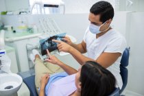 Молодой стоматолог-мужчина осматривает рентген с пациенткой в клинике — стоковое фото
