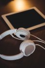 Nahaufnahme von Kopfhörern und digitalem Tablet auf Holztisch zu Hause — Stockfoto