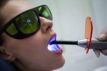 Zahnarzt untersucht Patientenzähne mit Zahnheillicht in der Klinik, Nahaufnahme — Stockfoto