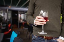 Mid section of man holding glass of wine in bar — Stock Photo