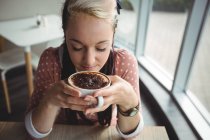 Mujer tomando una taza de café en la cafetería - foto de stock