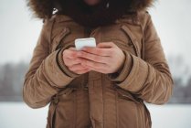 Mulher de casaco de pele usando telefone celular durante o inverno — Fotografia de Stock