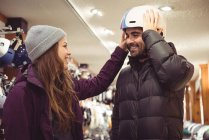 Casal selecionando capacete juntos em uma loja — Fotografia de Stock