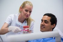 Dentiste montrant un ensemble de dents modèles au patient dans une clinique dentaire — Photo de stock