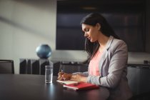 Businesswoman writing in diary in office — Stock Photo