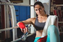 Portrait of tired female boxer sitting in ring in fitness studio — Stock Photo