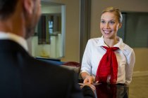 Personale femminile che dà la carta d'imbarco all'uomo d'affari alla reception del check-in — Foto stock