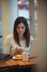 Geschäftsfrau benutzt Handy mit Laptop auf Tisch am Tisch — Stockfoto