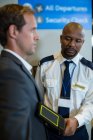 Oficial de segurança do aeroporto usando um detector de metais de mão para verificar um viajante no aeroporto — Fotografia de Stock