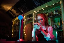 Cameriera utilizzando il suo telefono cellulare al bancone nel bar — Foto stock
