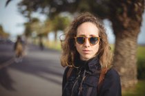 Primer plano de la mujer con gafas de sol en la carretera de la ciudad - foto de stock