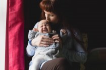 Mãe afetuosa consolando bebê chorando em casa — Fotografia de Stock