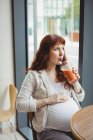 Donna d'affari incinta che ha succo di frutta in mensa ufficio — Foto stock