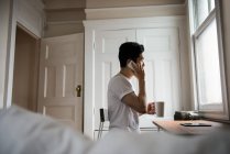 Homem falando no celular enquanto toma uma xícara de café em casa — Fotografia de Stock