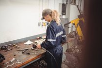 Meccanico femminile che controlla una macchina parti in garage di riparazione — Foto stock