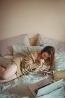 Mulher bonita usando tablet digital e laptop na cama em casa — Fotografia de Stock
