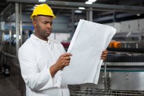 Trabalhador masculino sério lendo instruções na fábrica de suco — Fotografia de Stock