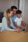 Famille utilisant un ordinateur portable dans le salon à la maison — Photo de stock