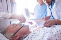 Команда врачей надевает кислородную маску на лицо пожилого мужчины в больнице — стоковое фото