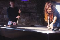 Giovane coppia felice giocare a biliardo nel bar — Foto stock